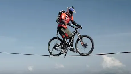 Fenomenal! Tipul asta reuseste sa treaca cu bicicleta la altitudinea asta pe o sfoara ingusta! Este extrem de periculos si dificil